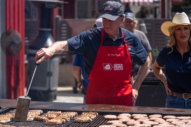 Doug Burgum, Governor of North Dakota, flips pork burgers at the Iowa Pork Tent, on Thursday, Aug. 10, 2023, at the Iowa State Fair, in Des Moines.