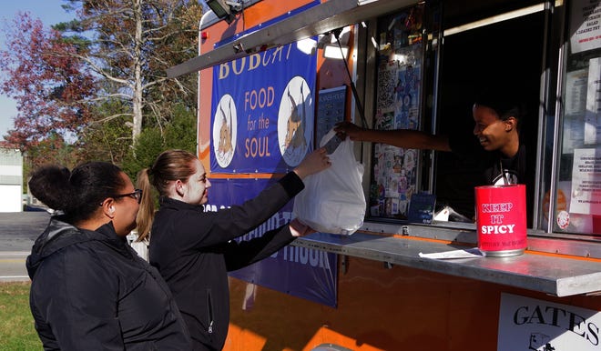 Brenda Veras and Kayla Labsan of Taunton get lunch consisting of Loaded Fries and Tacos from Kimyana Dardy at the Bobcats food truck on Rte 44 in Taunton on Friday, Nov. 3, 2023.