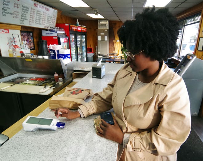 Jandira Sanches of Brockton, originally from Cape Verde, places her Visa card in the card reader and fills in her info on Visa card in order to pay for her meal on Tuesday, Nov. 14, 2023, at the Supreme House of Pizza in Brockton. The restaurant recently started taking credit and debit cards after being strictly cash for many years.