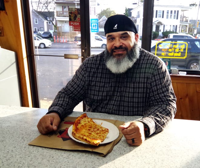 Noel Sierra of Providence who grew up in Brockton, prepares to enjoy a couple of slices of pizza on his way home on Tuesday, Nov. 14, 2023. Sierra's parents still live in Brockton, and while visiting them, stopping by the Supreme House of Pizza for some slices is part of strict ritual he maintains. He enjoys coming, says the staff is always friendly, and he considers the restaurant to be a big part of the Brockton neighborhood.