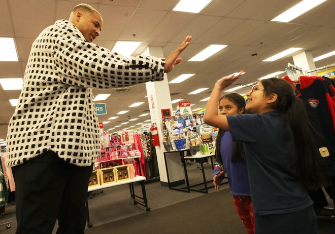 Customers Jhoanna Castro, 10, center, and Evelyn Chimbay, 7, get a high-five from New England Patriots tight end Pharaoh Brown at a surprise holiday payoff event at Brockton Citi Trends on Tuesday, Dec. 12, 2023. Customers had their layaway items paid off from a partnership between the nonprofit Pay Away and Brown.