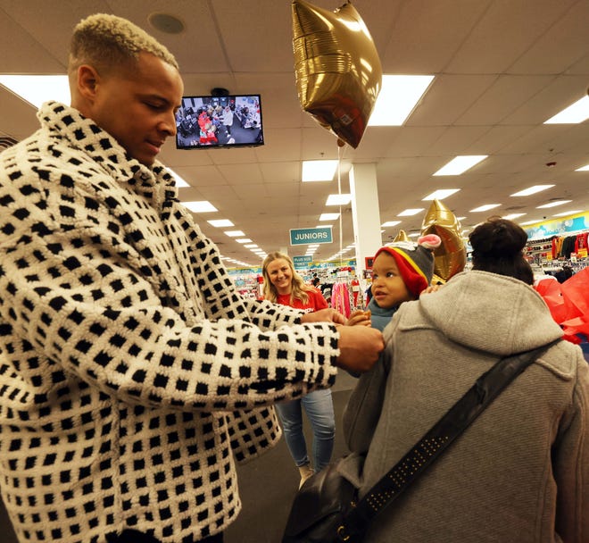 Customer Alondra Marte, with her son Abdias Marte, 2, who receives a balloon from New England Patriots tight end Pharaoh Brown at a surprise holiday payoff event at Brockton Citi Trends on Tuesday, Dec. 12, 2023. Customers had their layaway items paid off from a partnership between the nonprofit Pay Away and Brown.