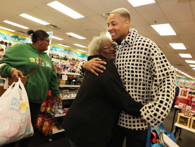 Customer Janis Williams hugs New England Patriots tight end Pharaoh Brown with Jaijai Mendes, left, at a surprise holiday payoff event at Brockton Citi Trends on Tuesday, Dec. 12, 2023. Customers had their layaway items paid off from a partnership between the nonprofit Pay Away and Brown.