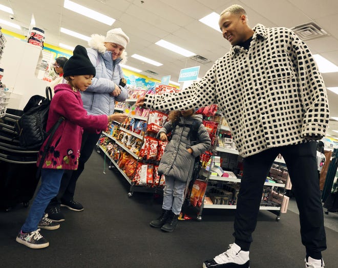 Customers Nicole Miller, Arianna Moniz, 9, and Amadeia Moniz, 6, give New England Patriots tight end Pharaoh Brown a lollipop at a surprise holiday payoff event at Brockton Citi Trends on Tuesday, Dec. 12, 2023. Customers had their layaway items paid off from a partnership between the nonprofit Pay Away and Brown.