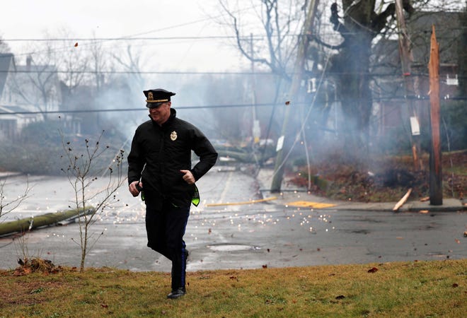 A Bridgewater police officer runs after a transformer blows up on a utility pole on Stetson and Pearl streets in Bridgewater during a storm on Monday, Dec. 18, 2023.